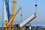 17-01-2023 Breda - Het laatste stuk van de mast van een 210 meter hoge windmolen hangt in de takels. De windmolen kwam in een bouwpakket aan en lag langere tijd te wachten om in elkaar gezet te worden. - Fotokrant